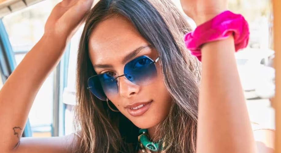 Woman wearing blue gradient sunglasses and a bright pink hair scrunchie.