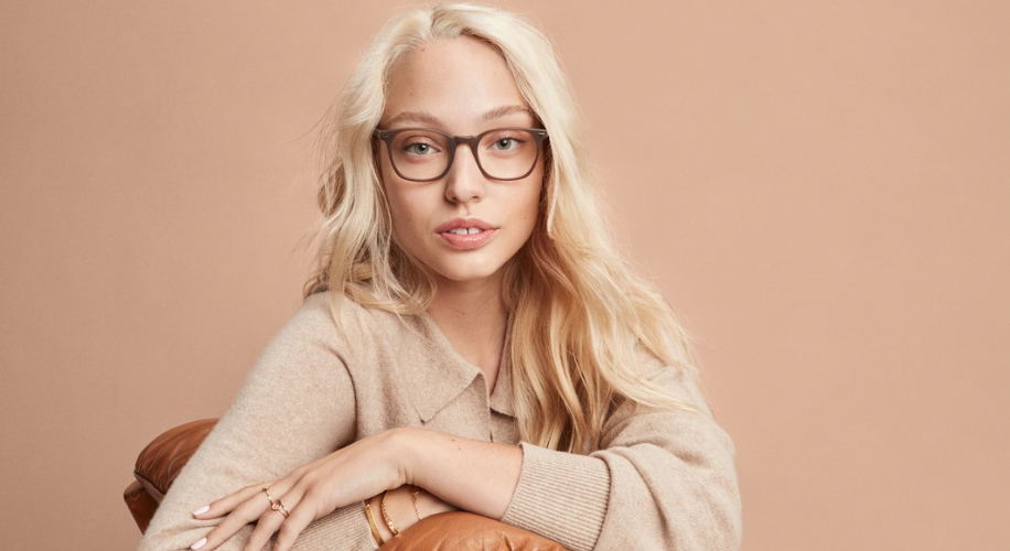 Blonde woman wearing brown eyeglasses and a beige sweater.