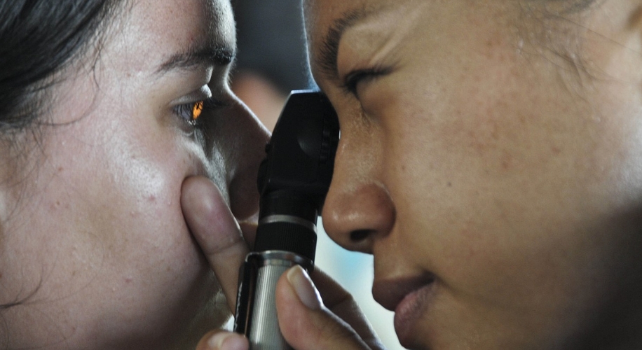 Optometrist examining a patient&#039;s eye with an ophthalmoscope.