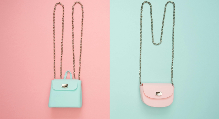 Two purses with chain straps: a mint green handbag with a flap and clasp, and a pink crossbody bag with a clasp.