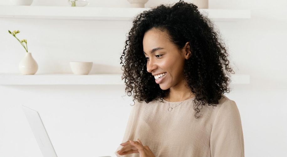 Woman smiling while using a laptop.