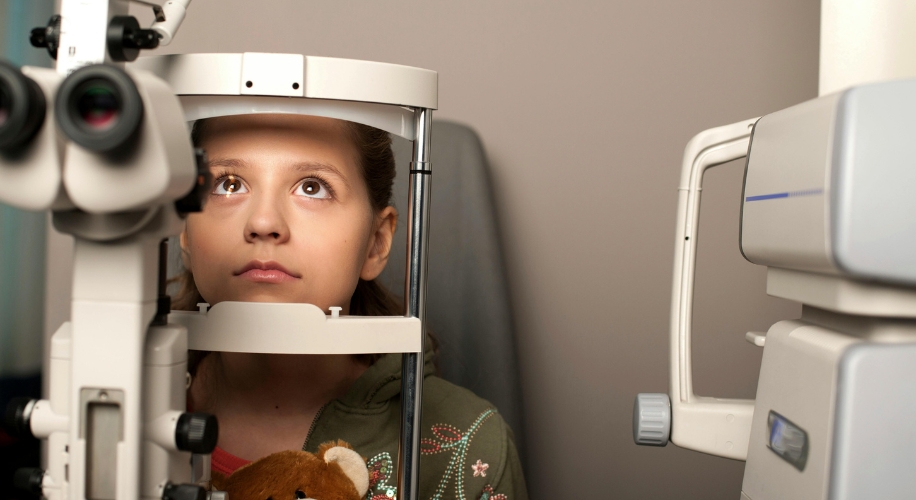 Young girl undergoing an eye examination using a phoropter.