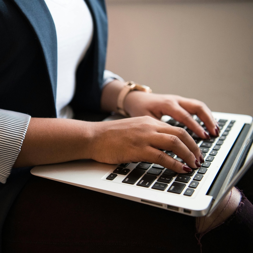 Person typing on a silver laptop keyboard.