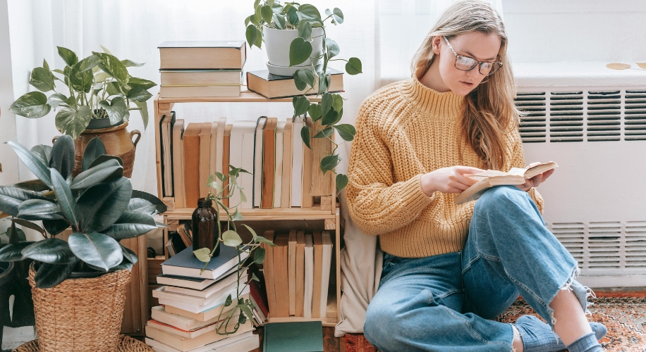 Girl sitting near bookshelf with potted plants