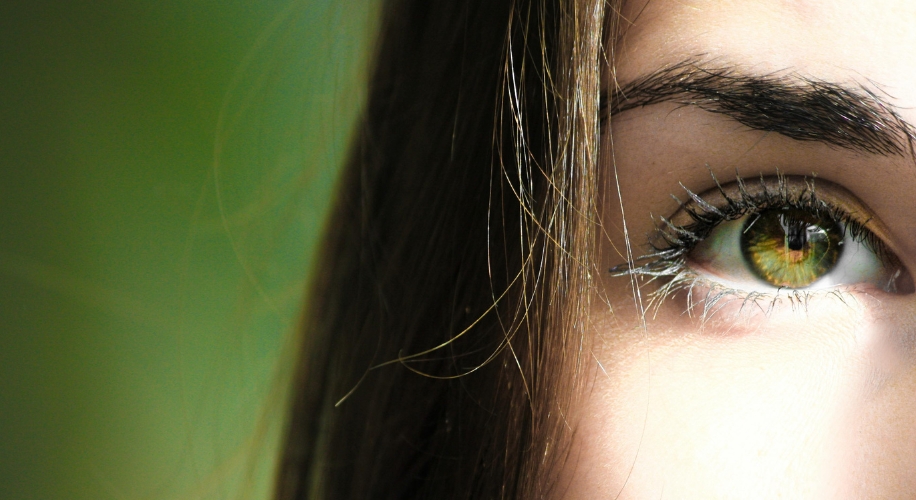 Green eye with long eyelashes and brown eyebrow, close-up shot.