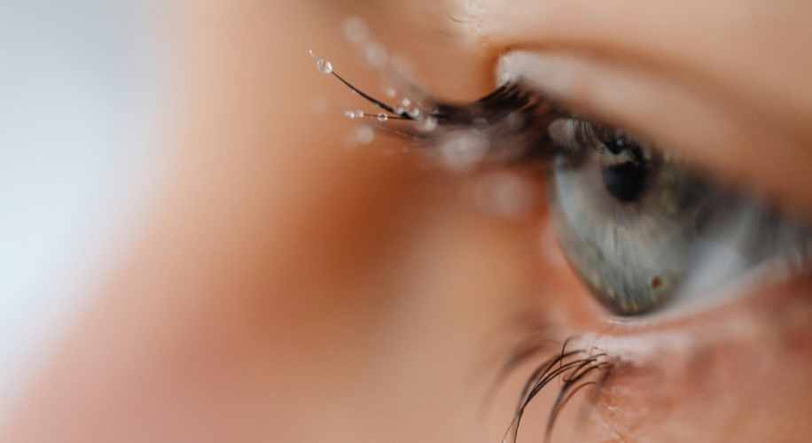 Close-up of an eye with water droplets on the eyelashes.