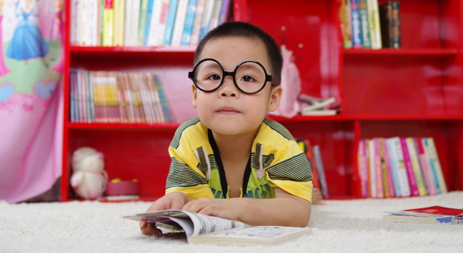 Boy looking at book with glasses on