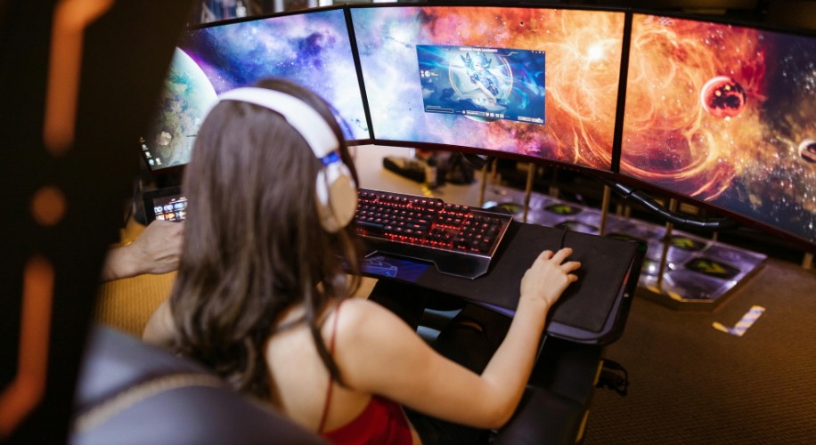 Person using a multi-monitor gaming setup with a RGB backlit mechanical keyboard and a gaming mouse.