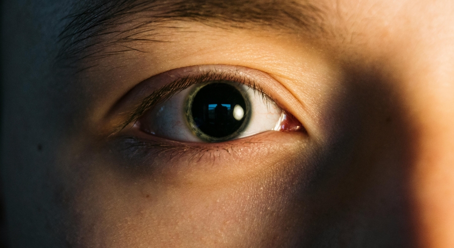 Close-up view of a human eye with light and shadow emphasizing the iris and pupil.