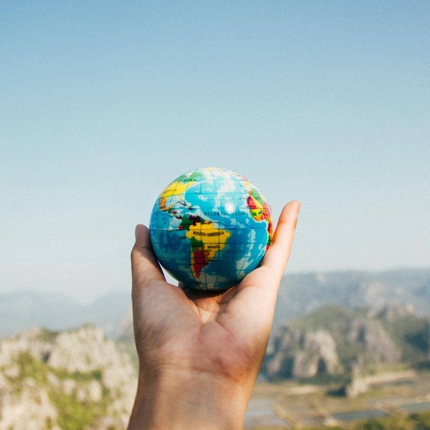 Hand holding a small globe showing continents and countries.