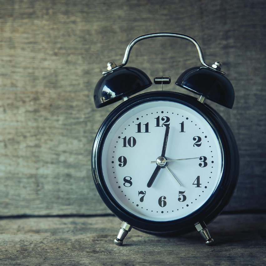 Black retro alarm clock with white face, black numbers, and silver hands displaying 9:21.