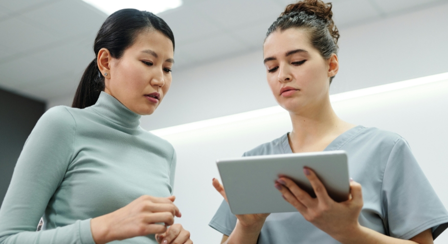 Two women looking at a digital tablet, focused on the screen, in a professional setting.