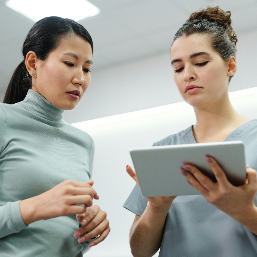 Two professionals discussing information on a tablet device.