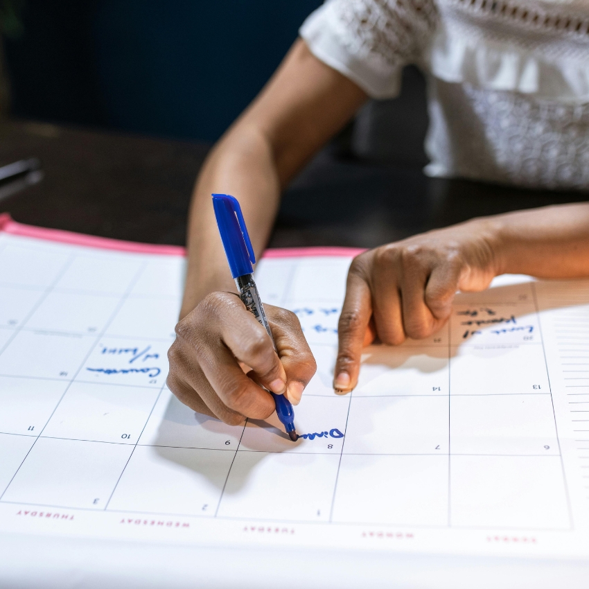 Hand writing on a calendar with a blue pen, the text "Dinner" is visible on April 8.