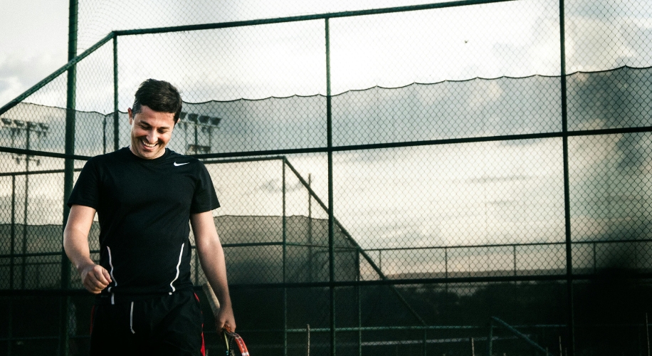 Man wearing a black Nike shirt holding a tennis racket on a tennis court.