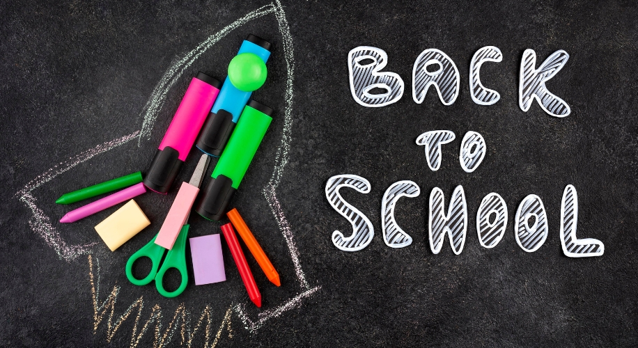 Back to School text on a chalkboard with colorful stationery items arranged in a rocket shape.