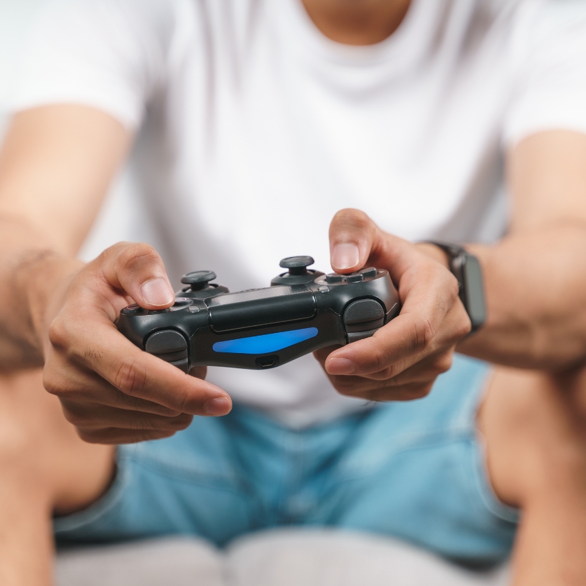 Hands holding a black gaming controller with a blue light bar in the center.