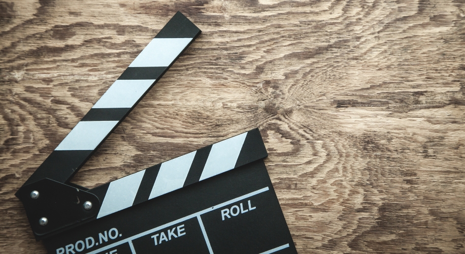 Film slate on a wooden surface. Text: PROD. NO., SCENE, TAKE, ROLL.