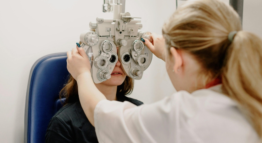 Optometrist using a phoropter to conduct an eye exam on a patient in a clinic.