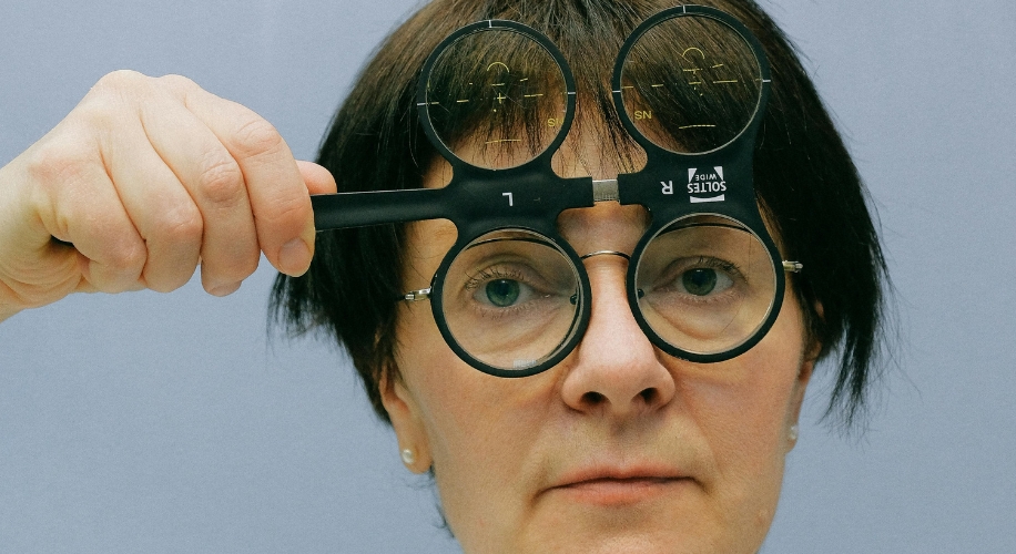 Eyewear test frame held by person for eye examination, labeled &quot;SN&quot;, &quot;R&quot;, &quot;1&quot;, &quot;L&quot;, “SN”, and &quot;SOITES VA VIA&quot;.