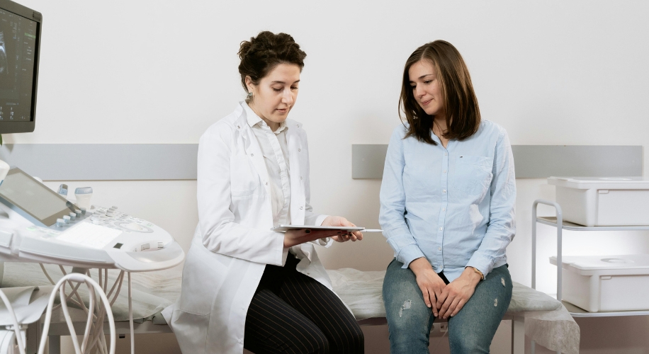 Doctor reviewing patient information with a woman sitting on an examination table.