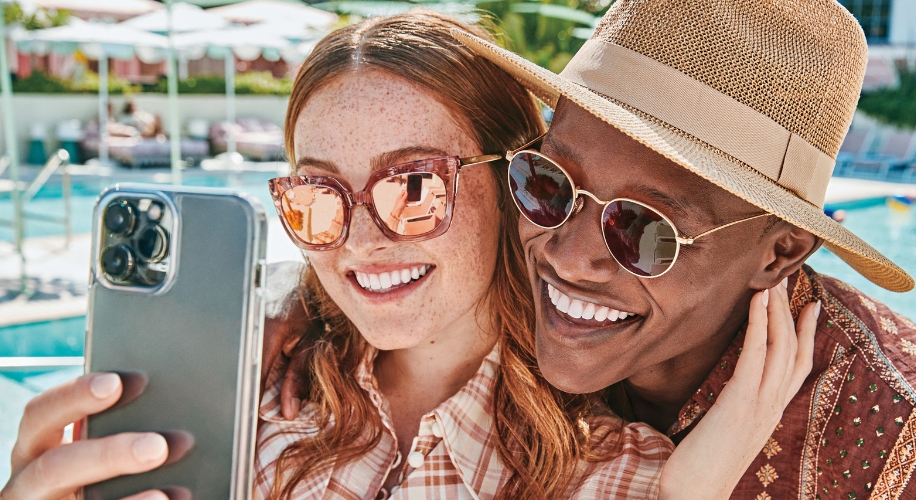 Two people smiling and posing for a selfie taken with a smartphone.