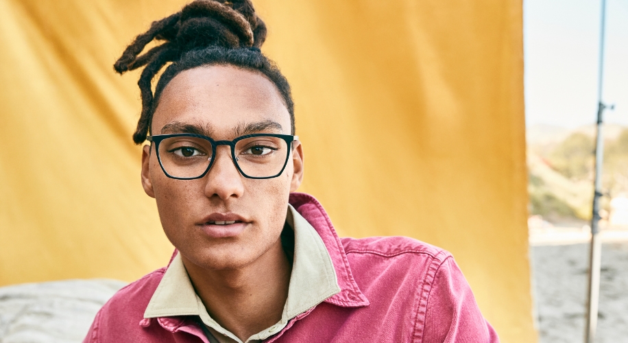 Person wearing black-framed glasses and a pink collared shirt.