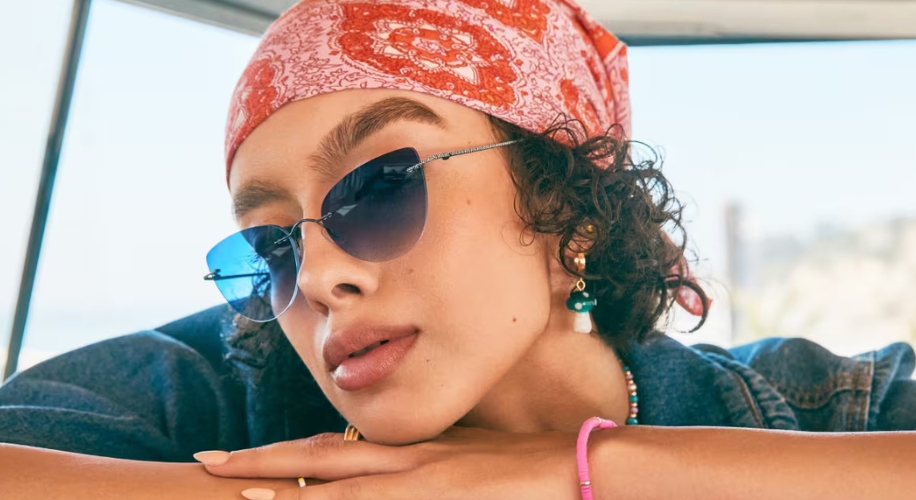 Woman wearing blue-tinted aviator sunglasses, red bandana, and blue jean shirt.