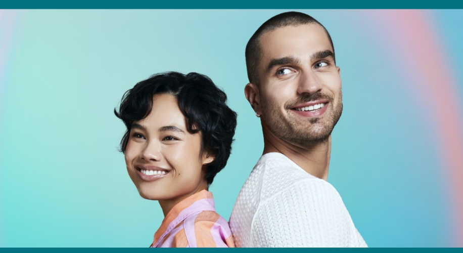 Man and woman standing back-to-back, smiling against a gradient blue and streak of pink background.