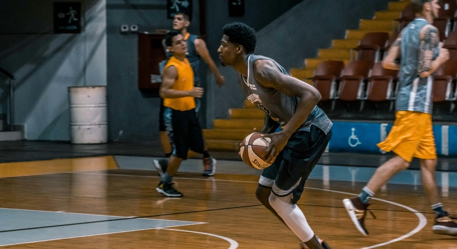 Basketball player dribbling the ball on an indoor court during a game.