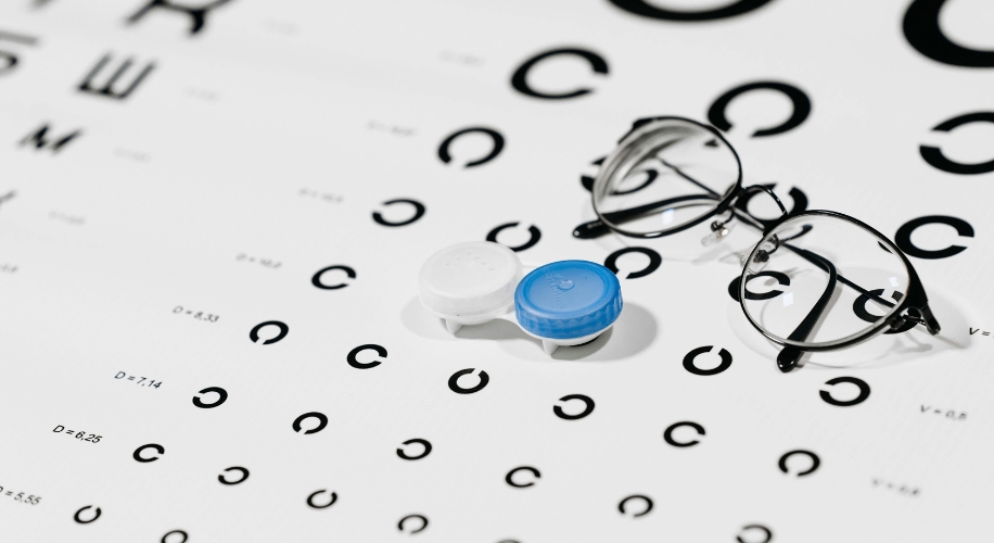 Contact lens case and eyeglasses on a vision test chart.