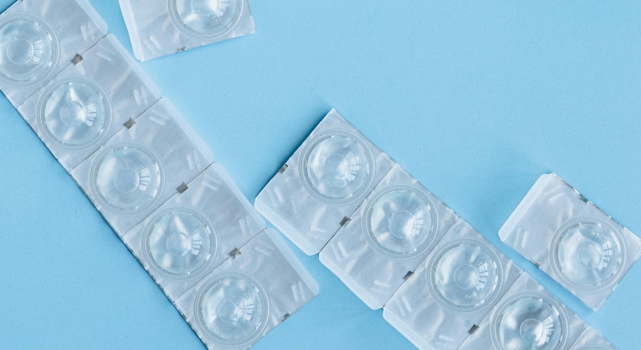 Blister packs of contact lenses on a blue surface.