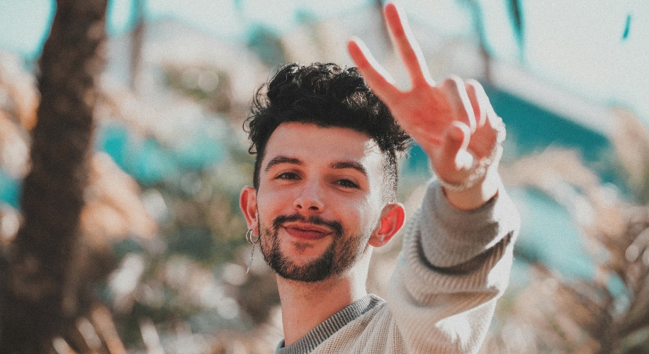 Smiling person making a peace sign with their hand.