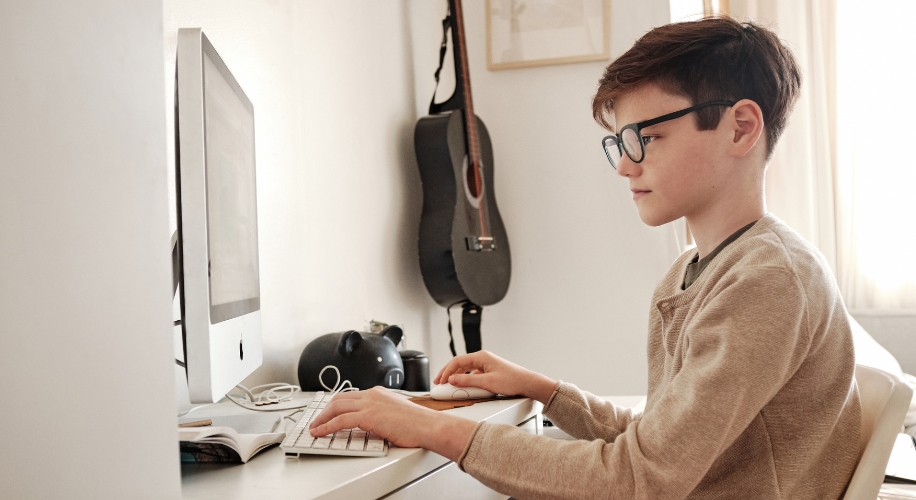 Young person using a desktop computer with keyboard and mouse.