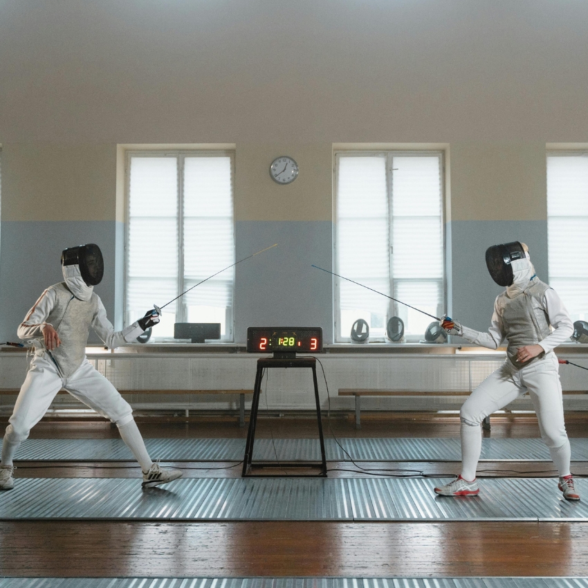 Two fencers in action; scoreboard shows 2 to 3 with a timer at 1:28:1.