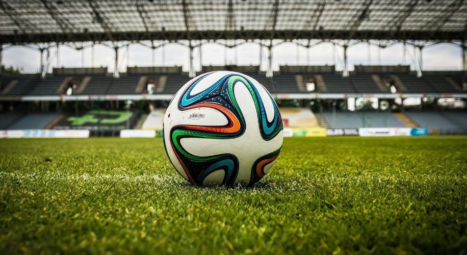 Soccer ball with colorful patterns on a grassy field inside a stadium.