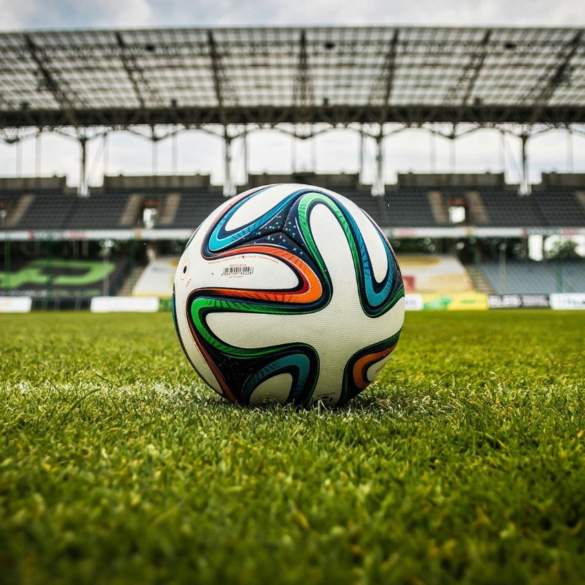 Colorful soccer ball with abstract patterns on green grass in a stadium.