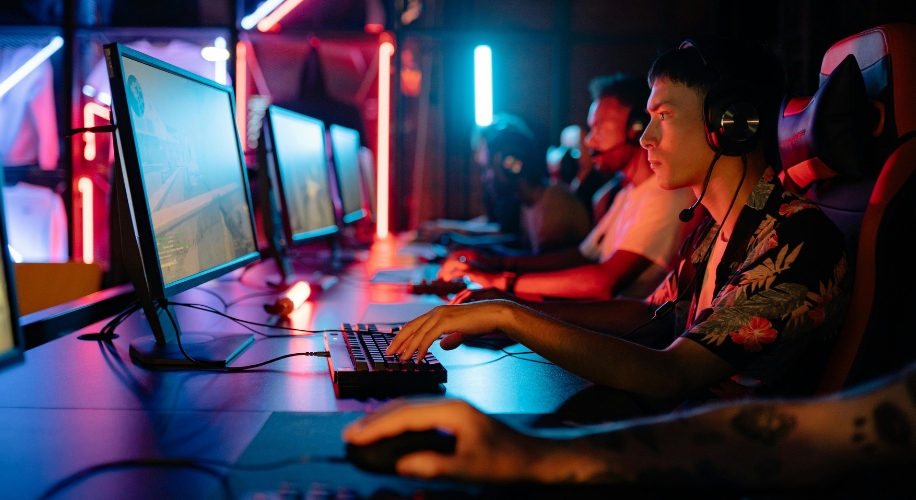 Gamers intensely focused on their game, using desktop computers with headsets at an esports event.