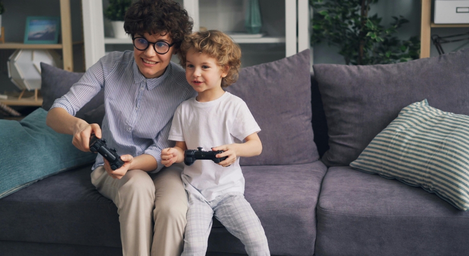 Two people on a grey couch playing video games with black controllers.