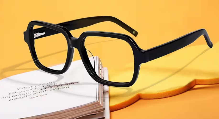 Square black eyeglasses with thick frames placed on an open book.