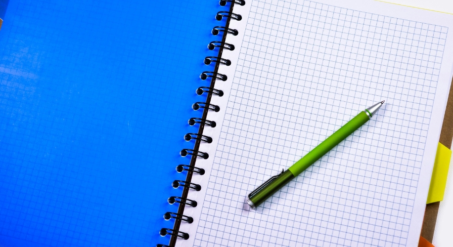 Spiral-bound notebook with a green pen on graph paper.