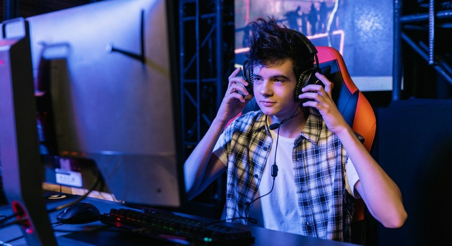 Person wearing headphones and sitting in a gaming chair in front of a computer monitor.