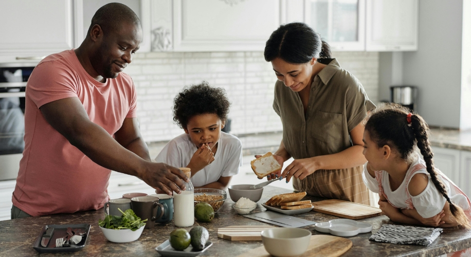 Family preparing sandwiches and snacks together in a modern kitchen.