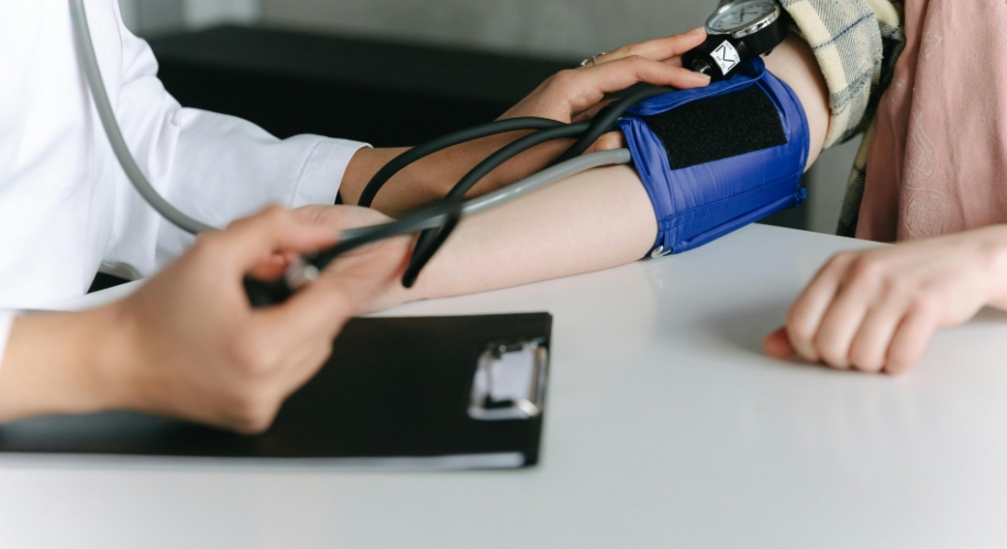 Blood pressure being measured with a blue arm cuff and black stethoscope.