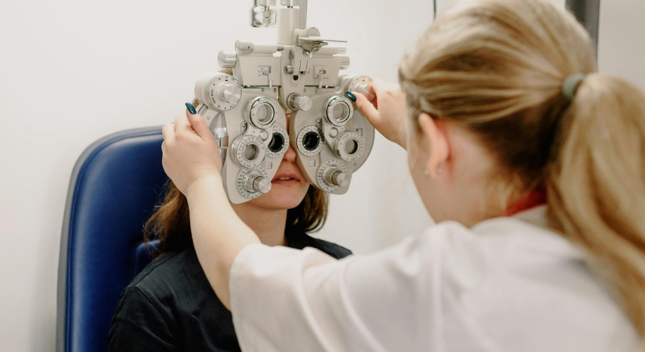 Ophthalmologist adjusting a phoropter for an eye examination on a patient.