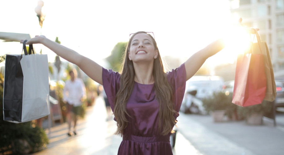 Person joyfully holding shopping bags in both hands.