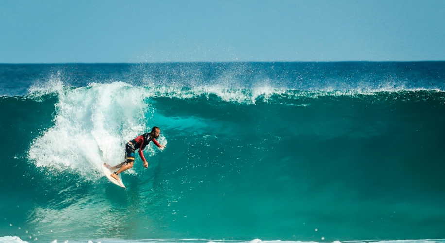 Surfer riding a large, turquoise wave.