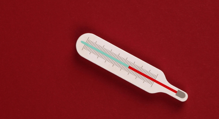 White thermometer with red and blue temperature markings on a red background.