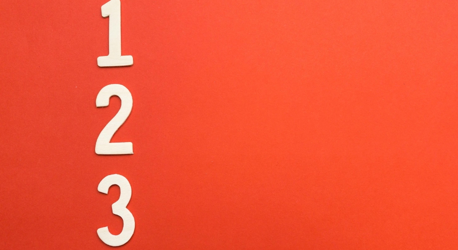 Wooden numbers &quot;1 2 3&quot; on a red background.