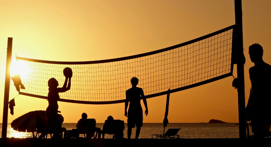 Silhouettes playing beach volleyball at sunset.